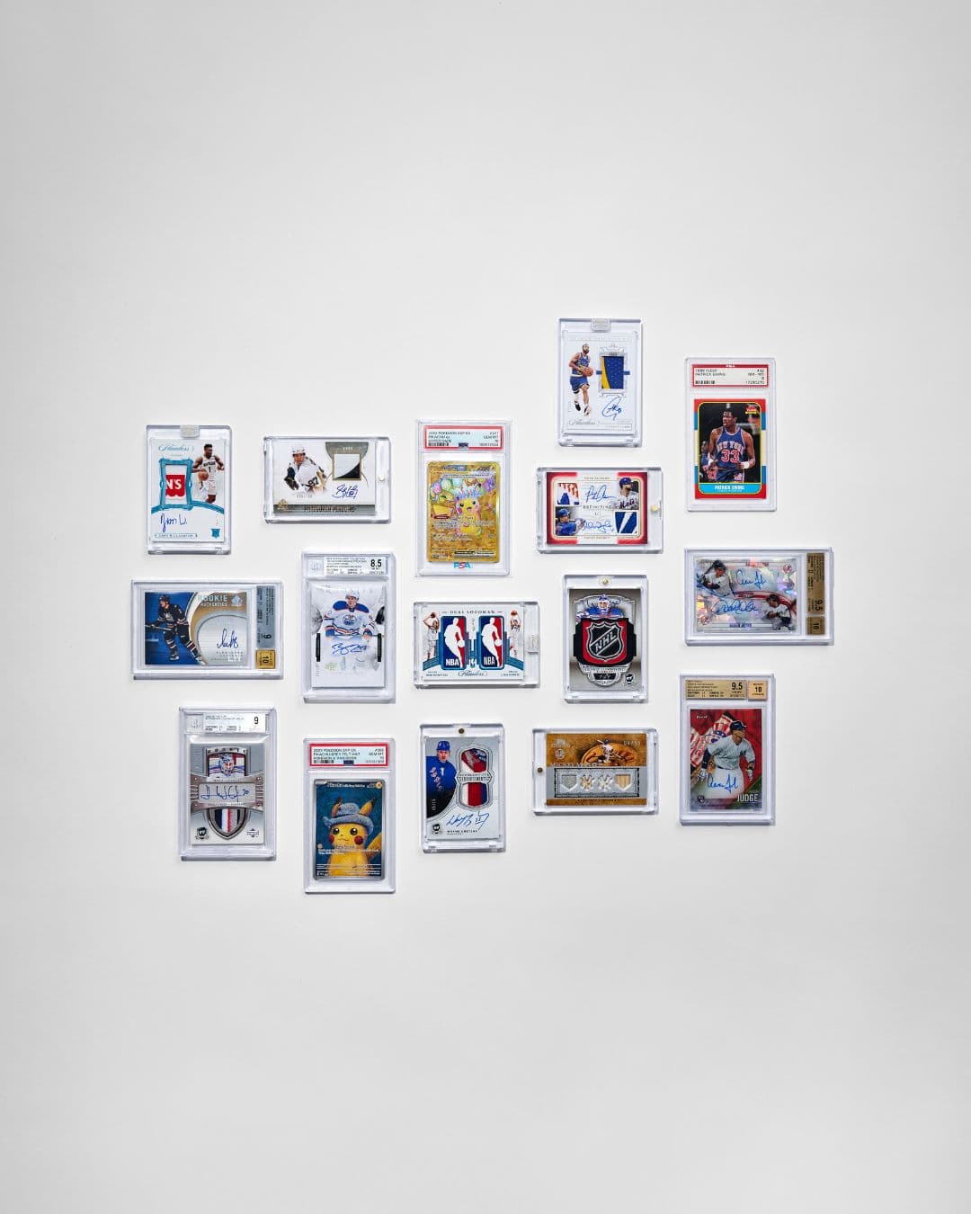 Graded sports and Pokémon trading cards displayed in a grid on a white wall.